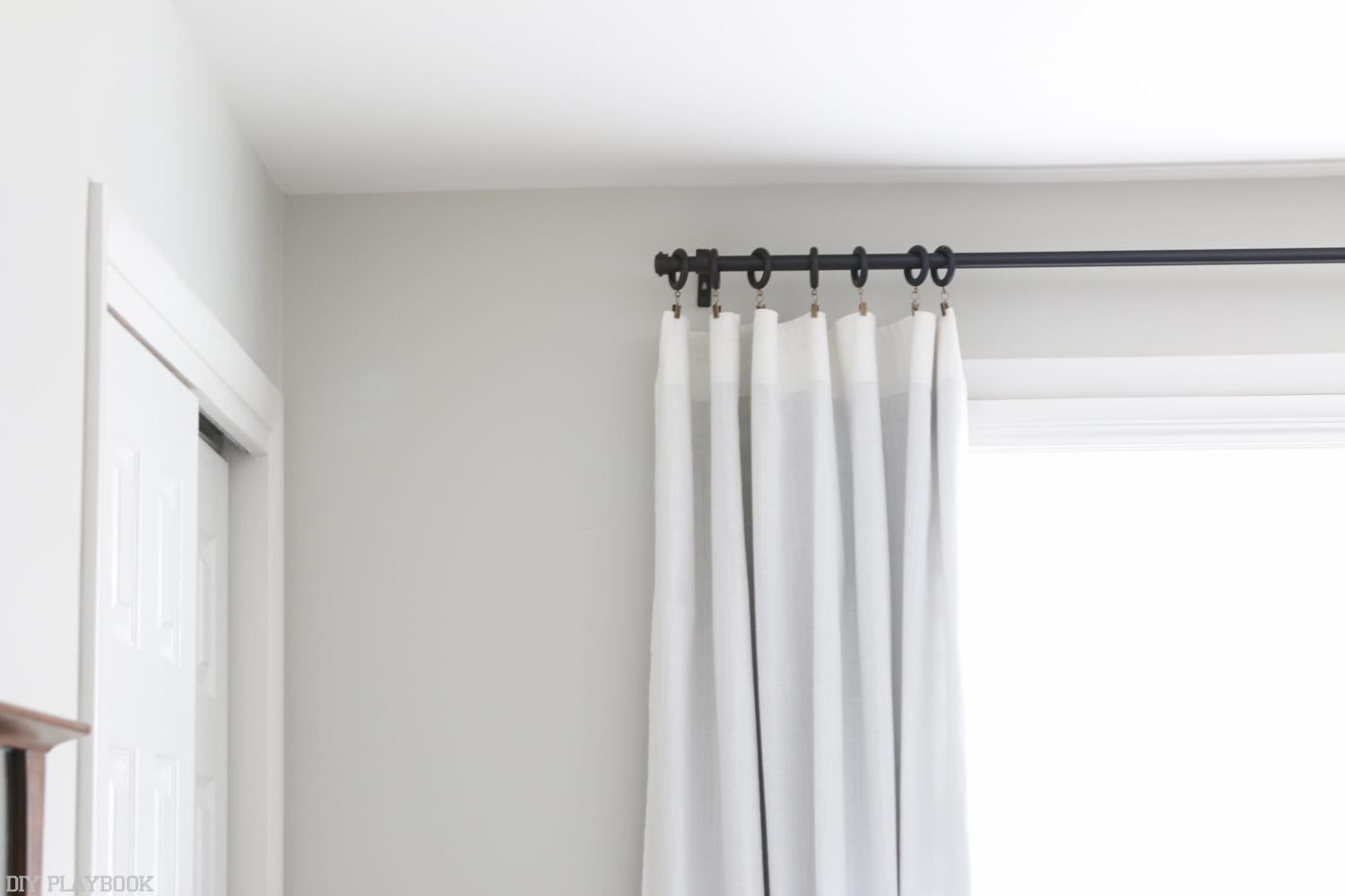 How to hang curtains high and wide to make your window appear larger