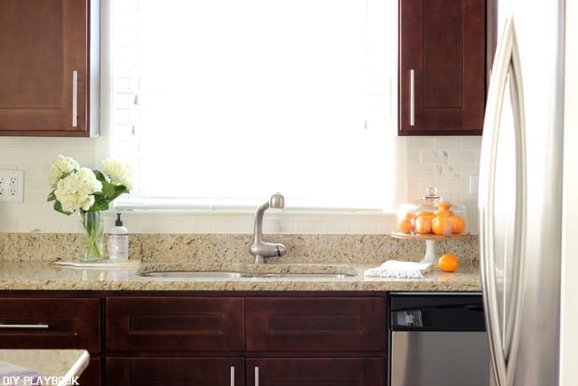 The white kitchen backsplash looks beautiful with the dark wood furnishings. 