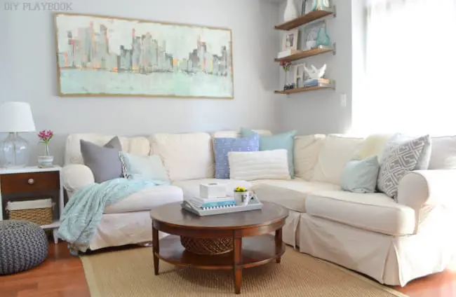 This cozy family room has pops of blue in the wall art and throw pillows. 