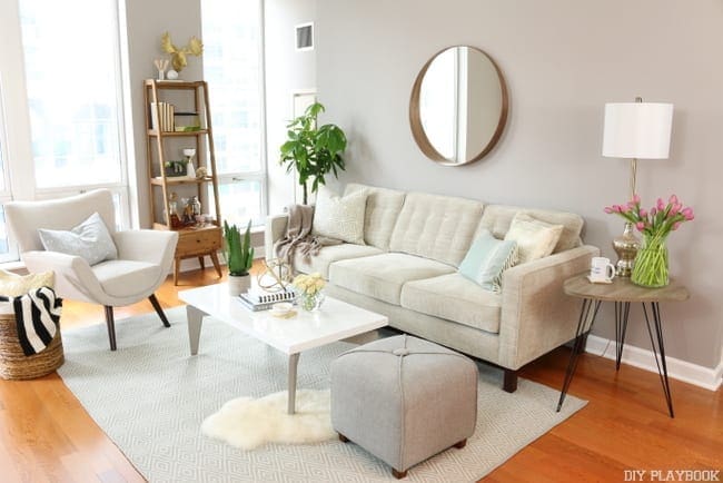 Condo living room with soft grey walls and light bright furniture after it was redecorated.