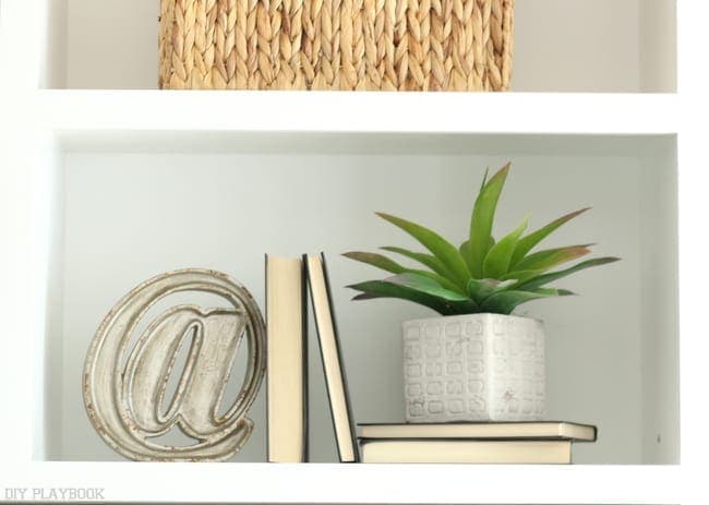 Bookshelf decorations; books, plants and decorative sign.