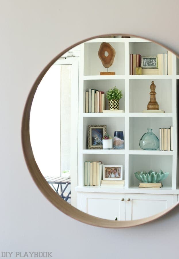 Living room wall mirror reflecting the bookshelves.