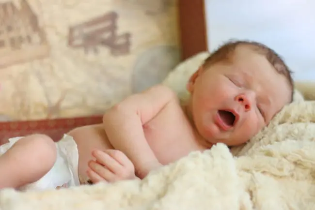 This adorable new born baby cuddles up with a blanket. 