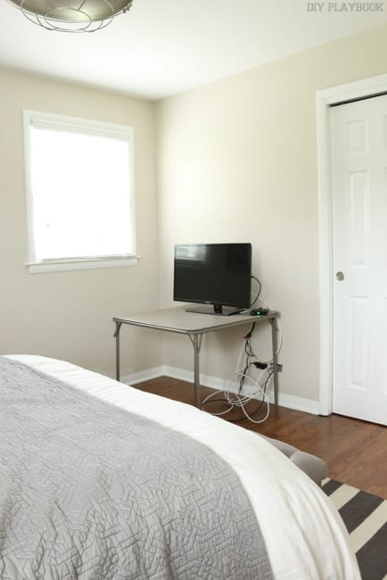 This neutral bedroom features lots of light and hard wood floors.
