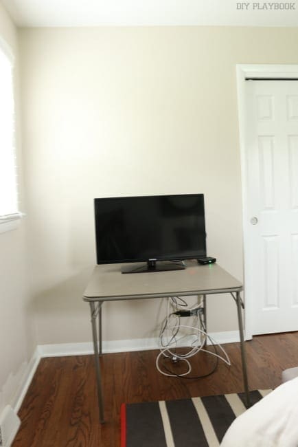 This before picture of the master bedroom features a TV resting on a card table. 
