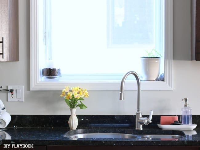 Sink area and yellow flowers without tile backsplash. 