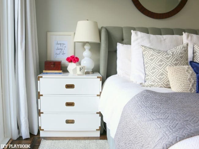 White campaign style nightstands look great in this white and blue bedroom. 
