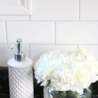 My white kitchen accessories like a hand soap dispenser and white hydrangeas look great with the white tile.