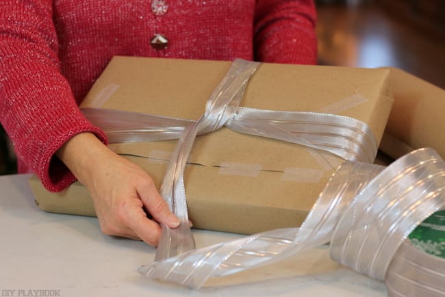 In order to tie the perfect bow, first you wrap the ribbon around the gift. 