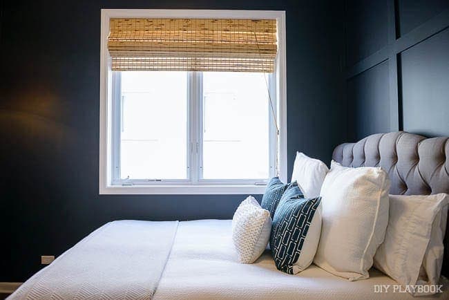 This bamboo window shade is an unexpected addition to the bedroom's decor. 