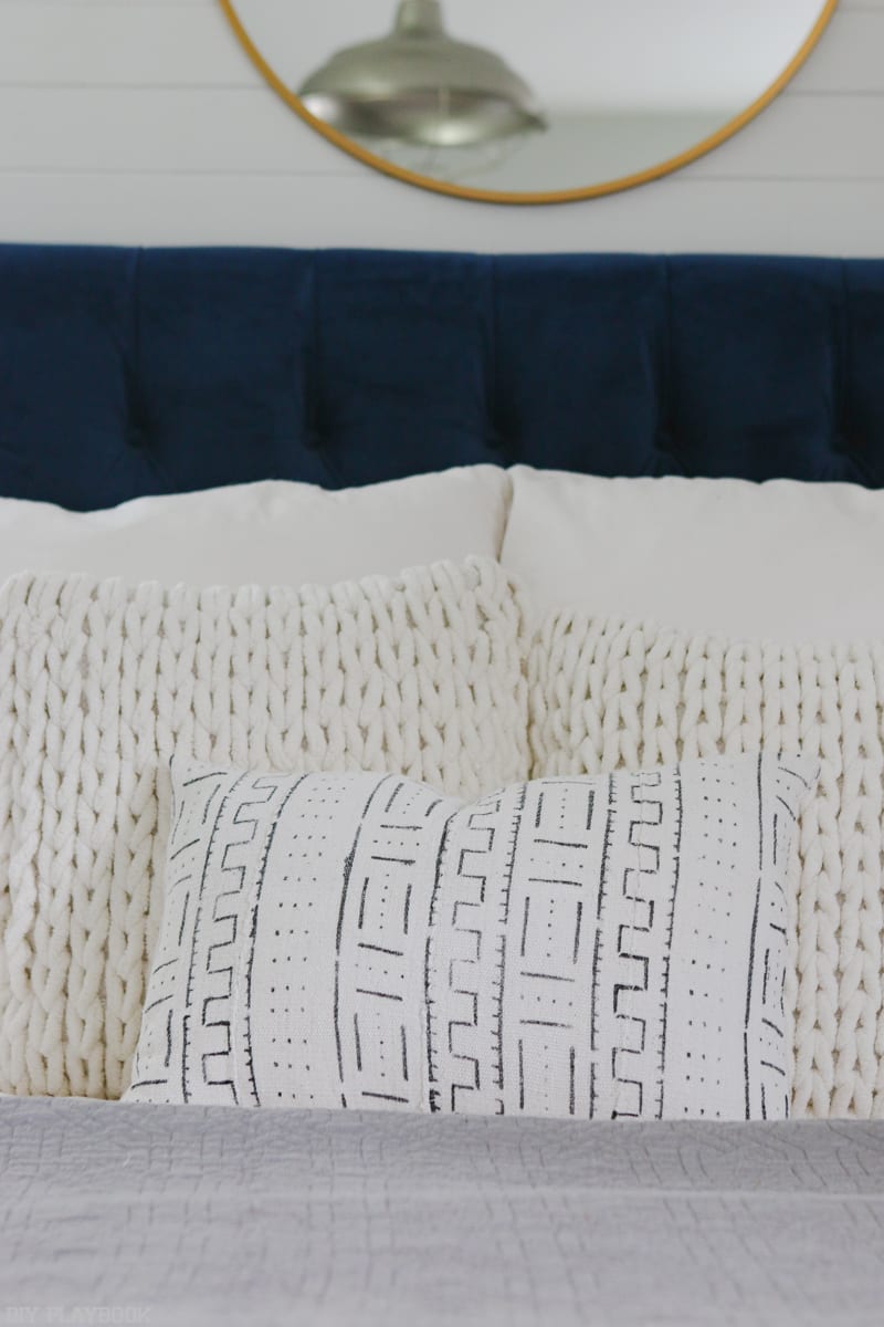 White throw pillows on a dark blue headboard.