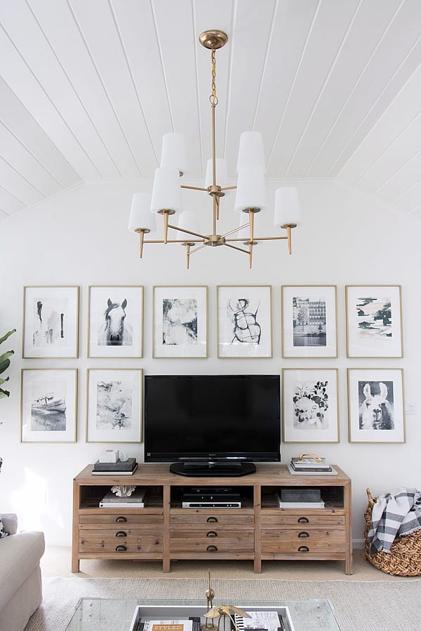 Simple black and white gallery wall designed around a TV - photo by Driven by Decor