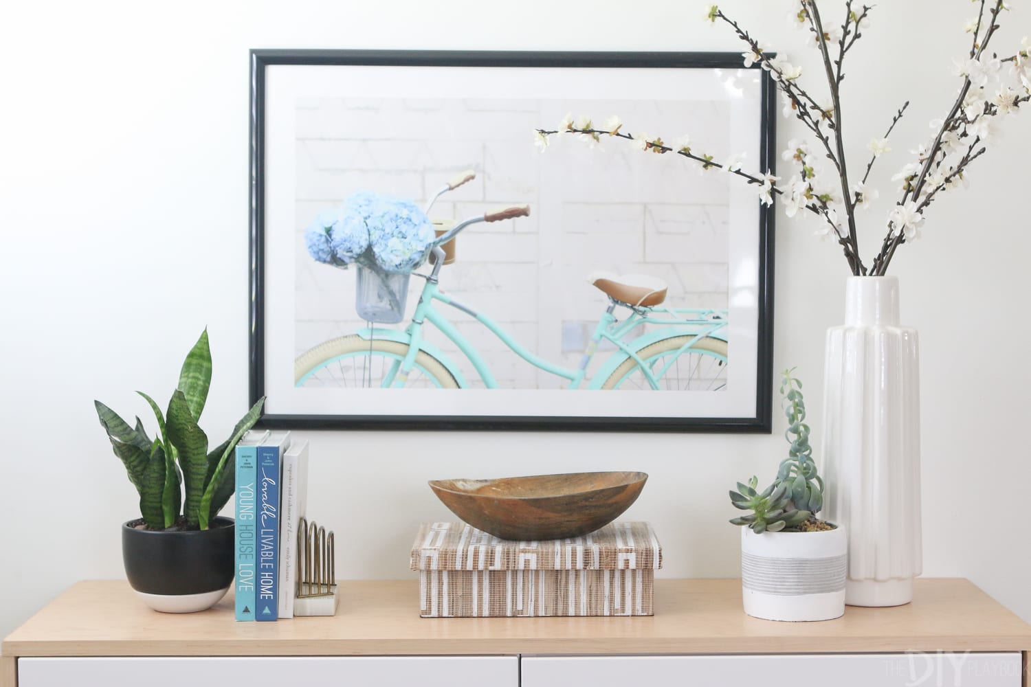 Bright turquoise bike with flowers in the basket print looks great above a sideboard with plants. 