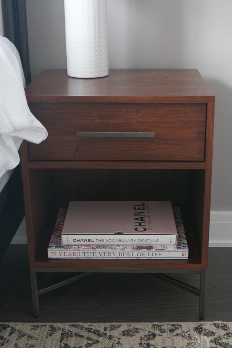 Modern brown wood nightstand with tabletop design books. 