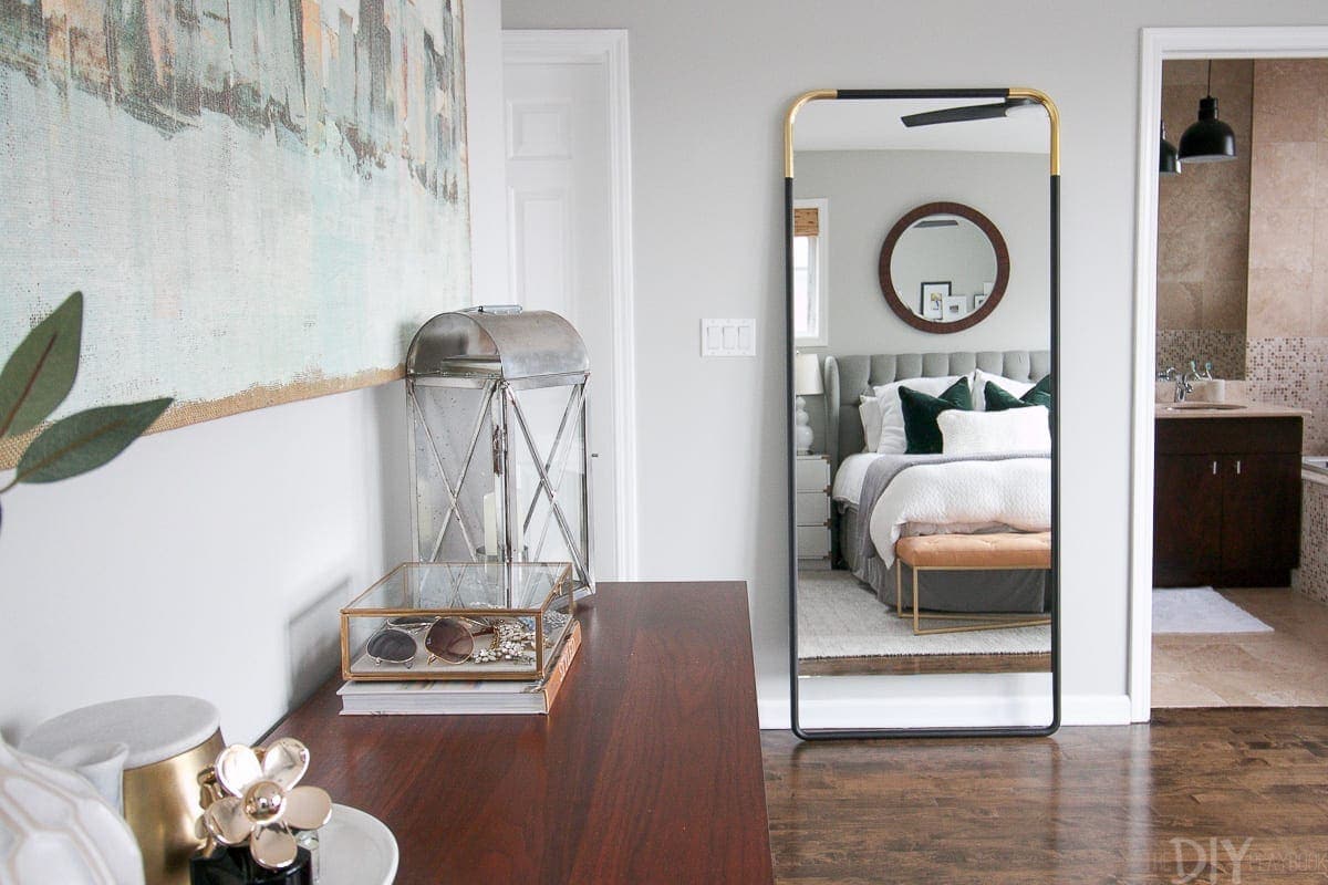 CB2 black and brass full-length mirror in a master bedroom space