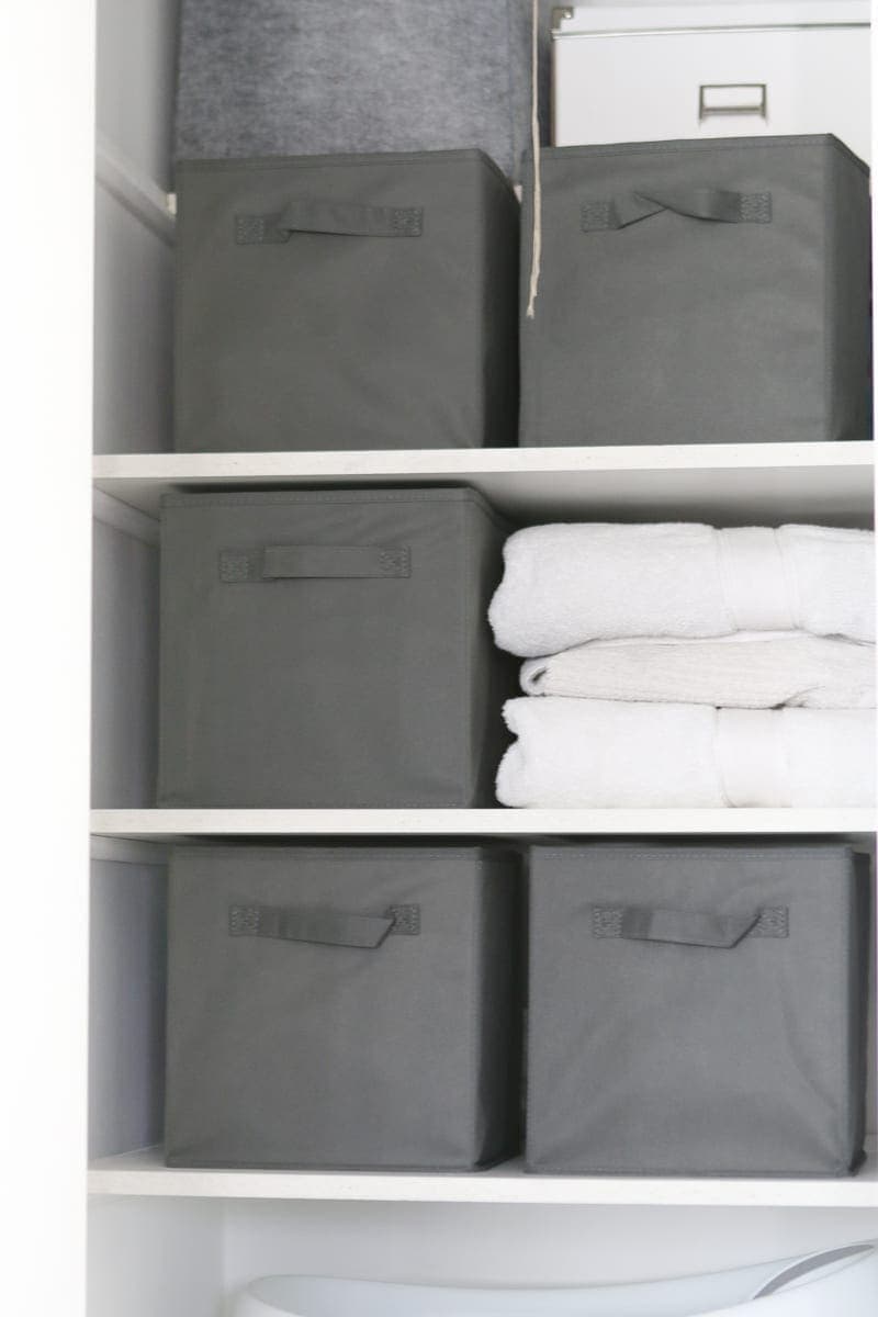 Organizing a linen closet with gray bins