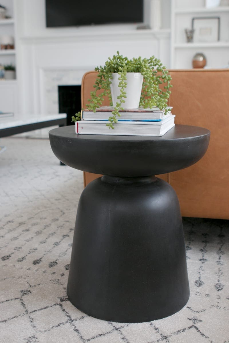 A round and black side table looks perfect next to a leather couch. 