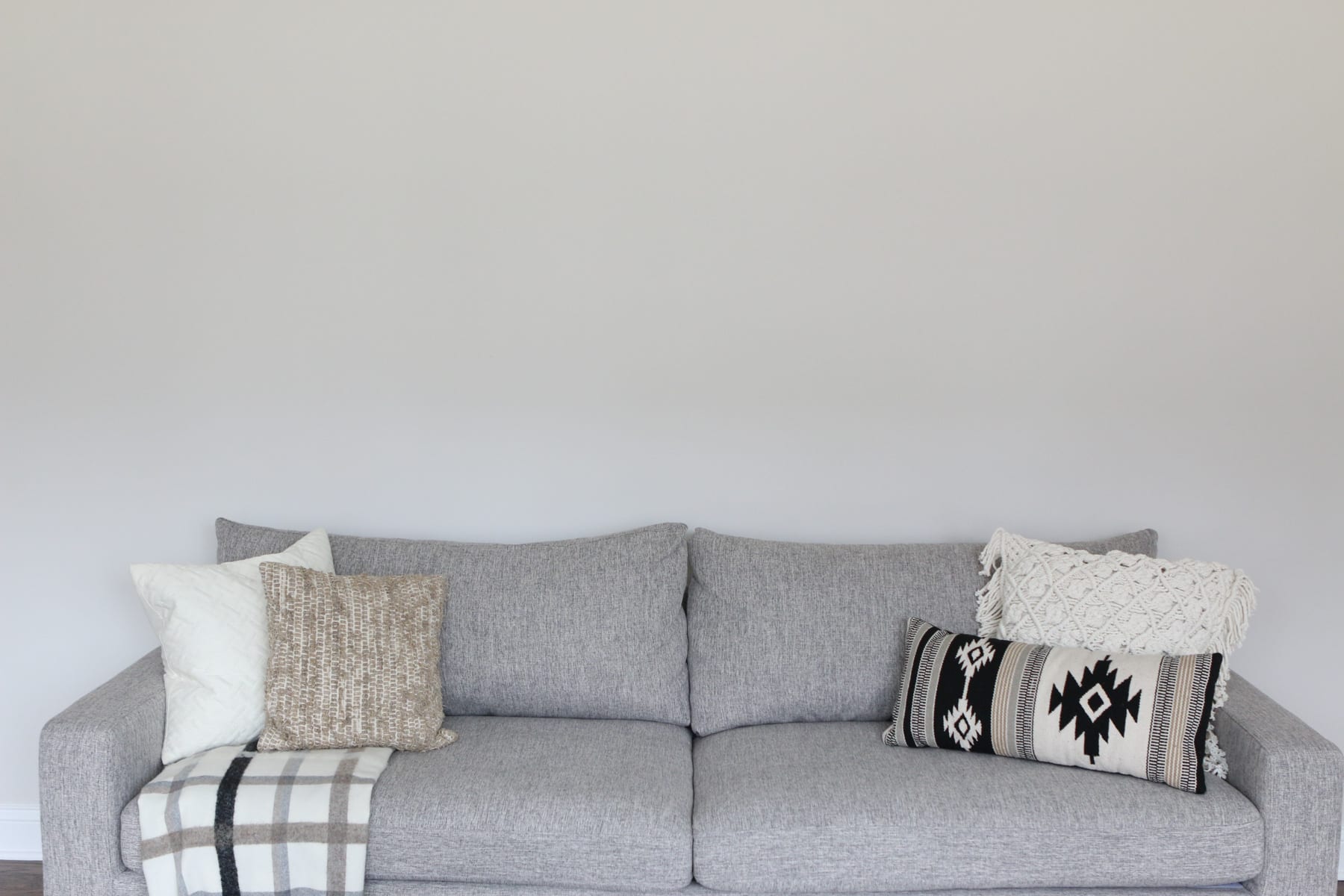 Blank wall over a gray couch in the family room. 