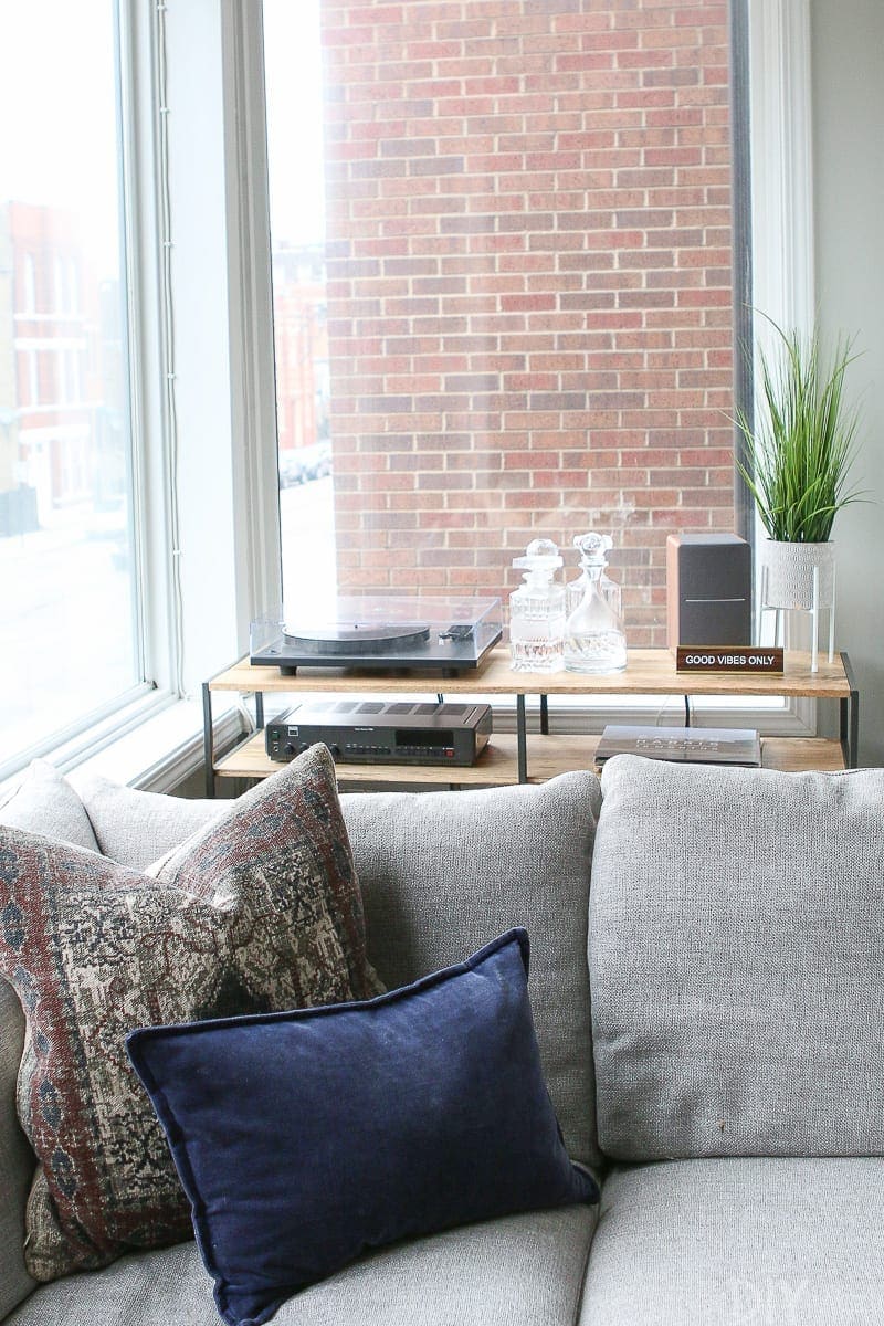 Record console behind a gray sectional in a family room space