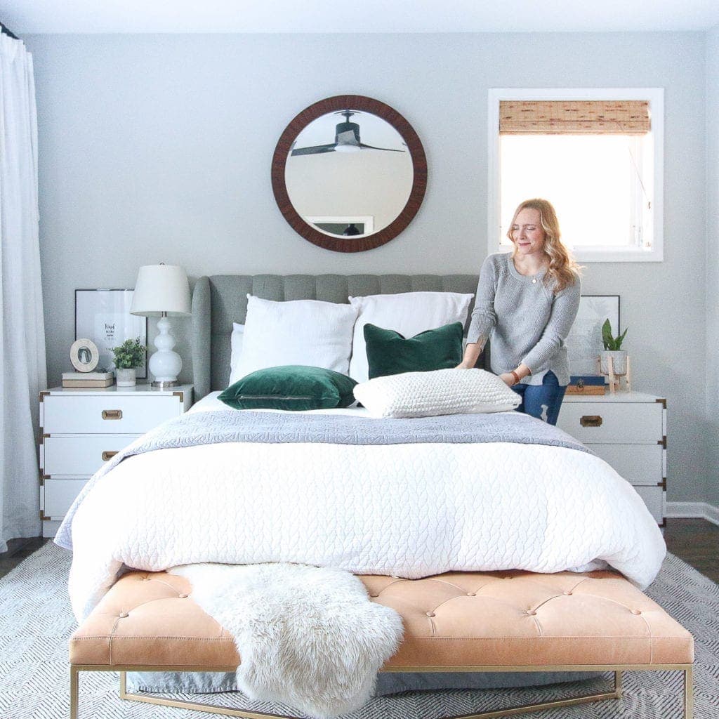 Making the bed in a neutral bedroom