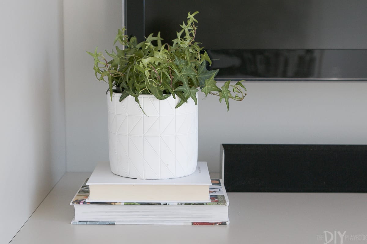 A white planter styled on top of a dresser of drawers. 