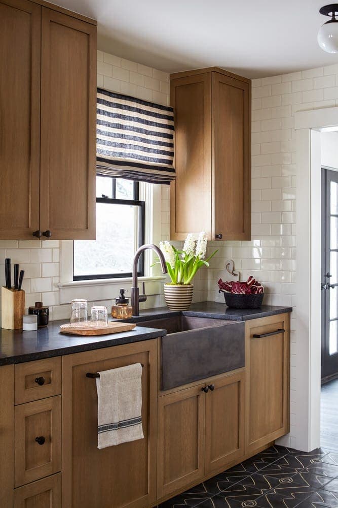 Love the white subway tile, wood kitchen cabinets, and black matte handles in this kitchen. 