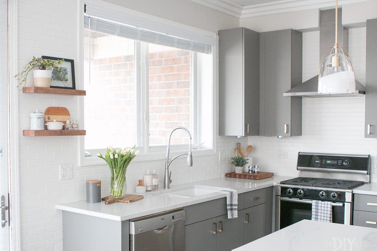 White backsplash with gray kitchen cabinets. 