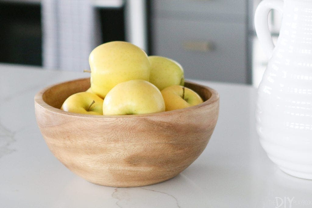 Display apples in a wood bowl for stylish kitchen decor.