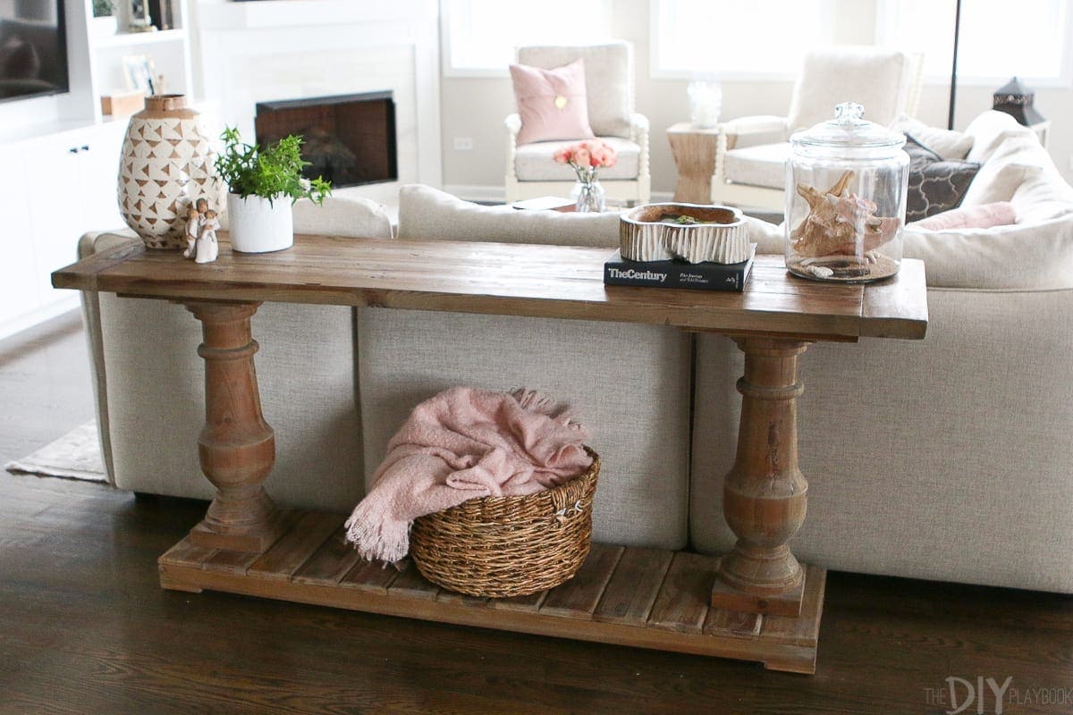 A wood console table provides storage and it hides the back of the couch. 