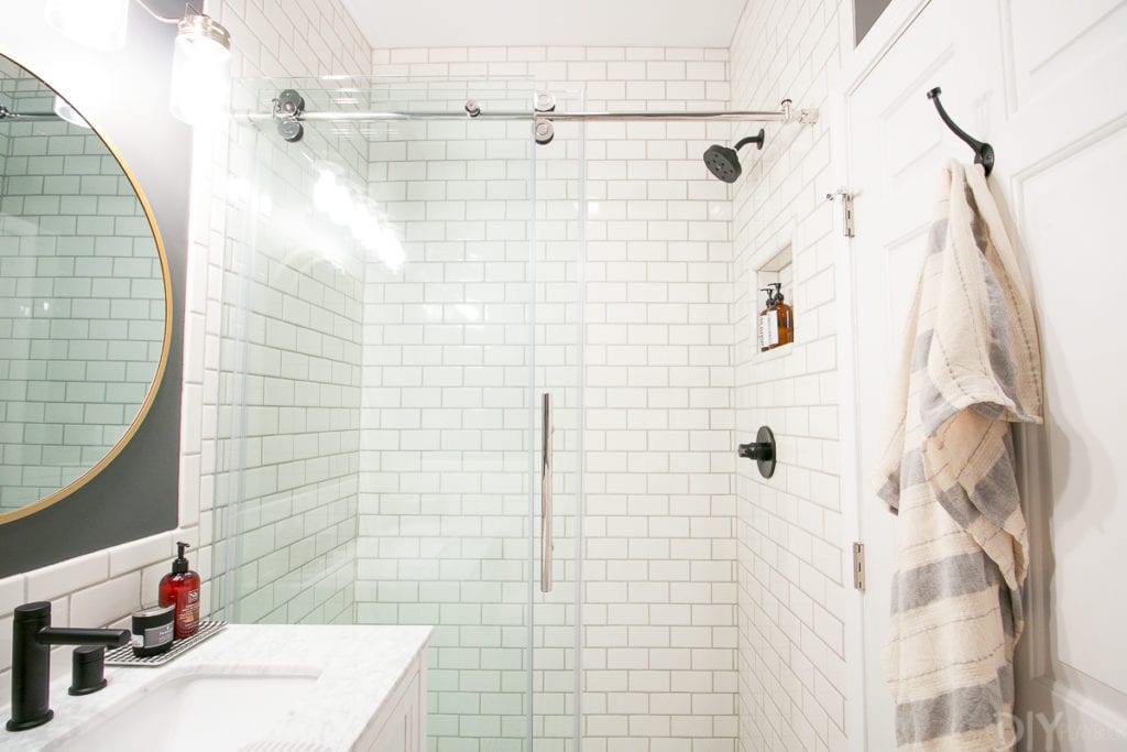 A white subway tile shower with black shower head