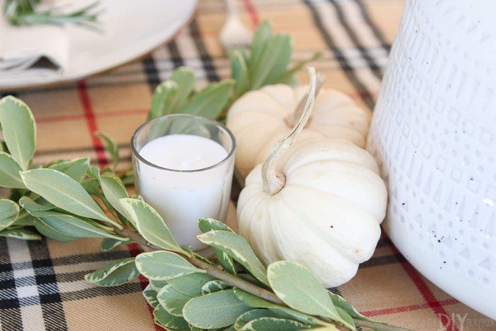 Candles, greenery, and white pumpkins work well on this tablescape