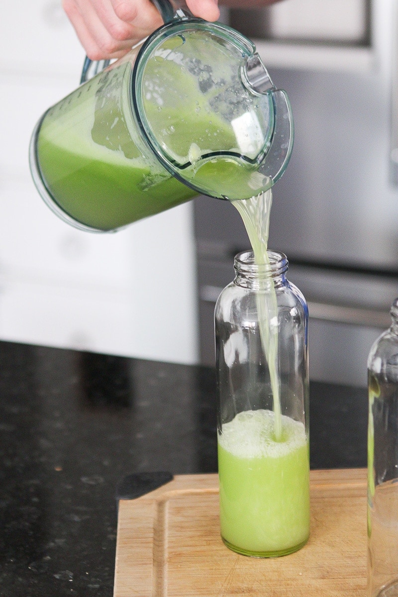 Pouring celery juice into glass bottles
