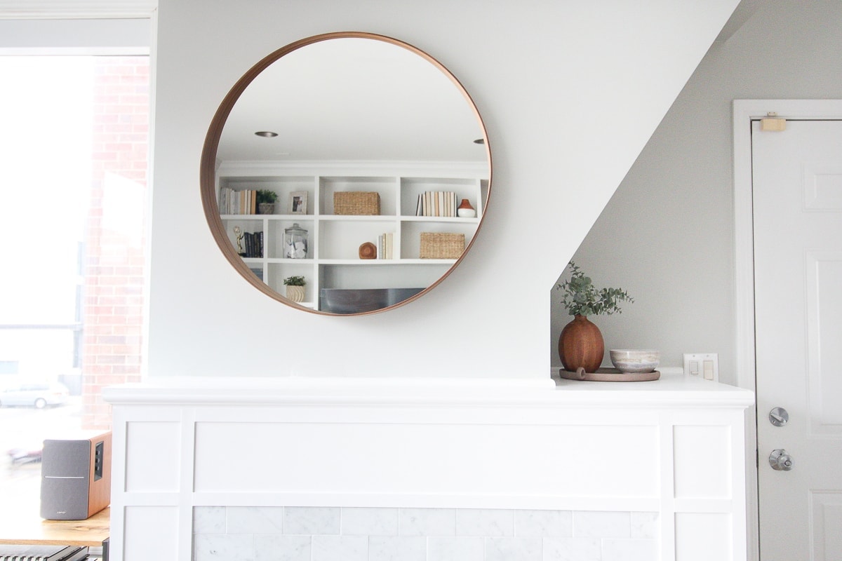 Round mirror above a fireplace