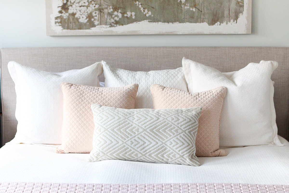 Blush and neutral pillows on a king-sized bed