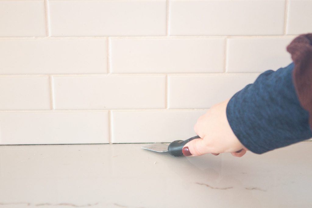 Scrape away the old grout