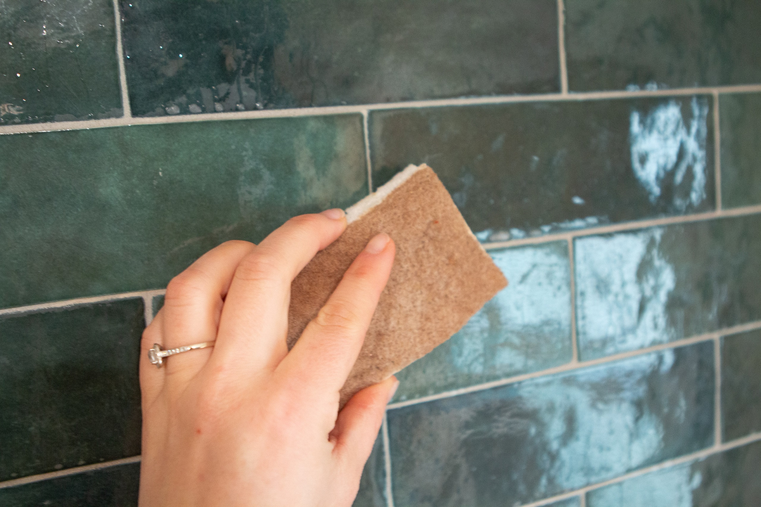 Use a sponge to put solution on the tile to remove grout haze