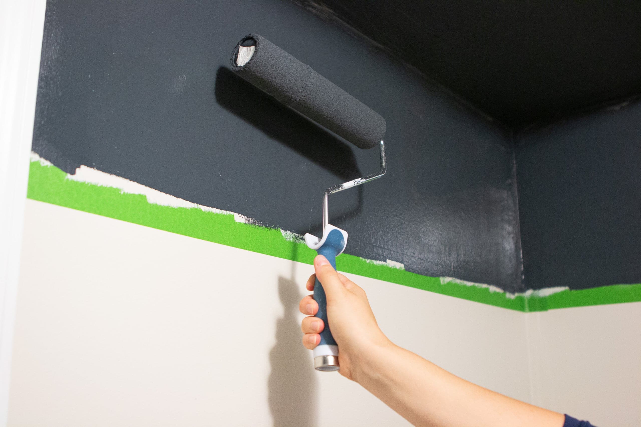 Using a roller to paint two-tone walls in a small bathroom