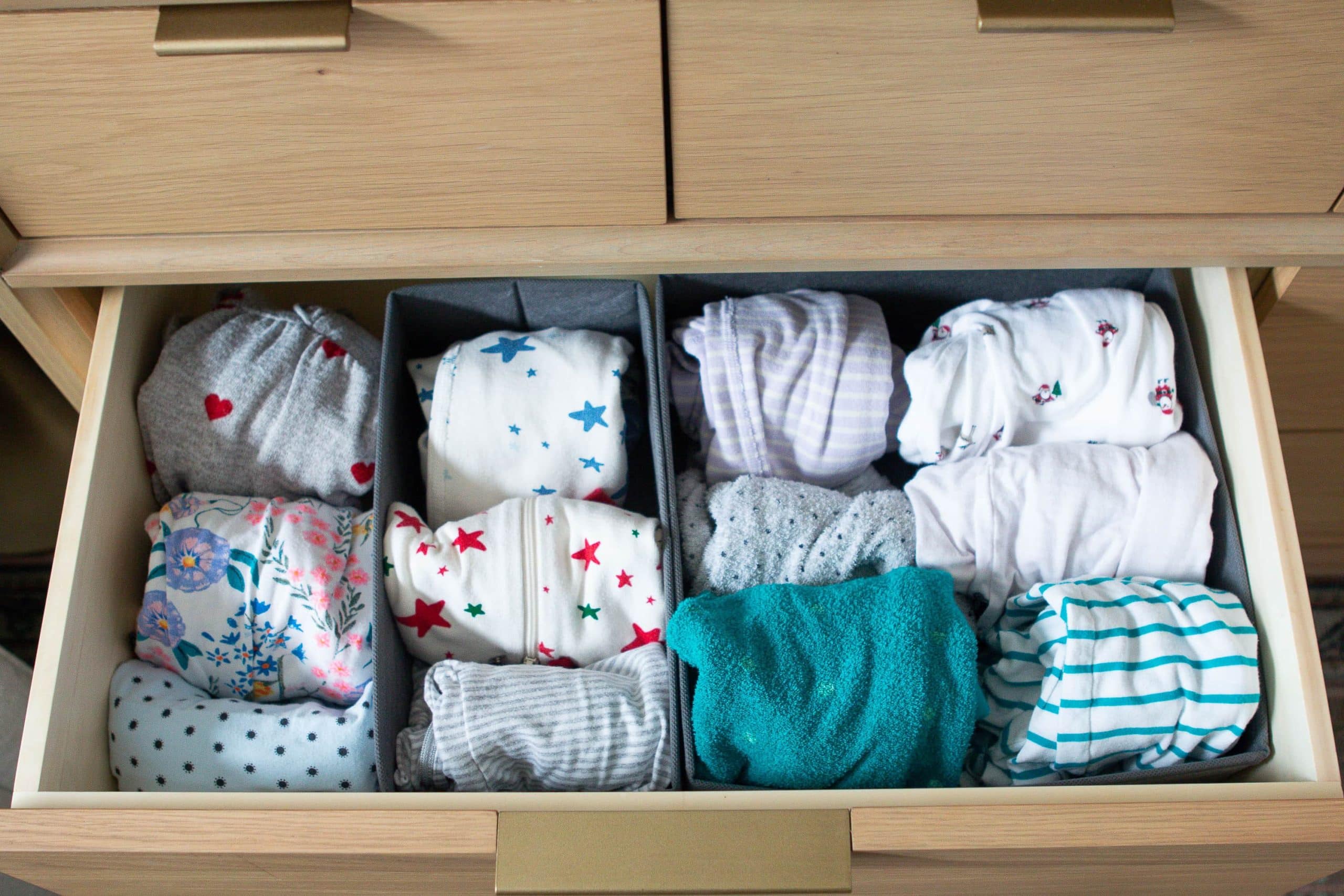 Organizing baby onesies in a dresser drawer