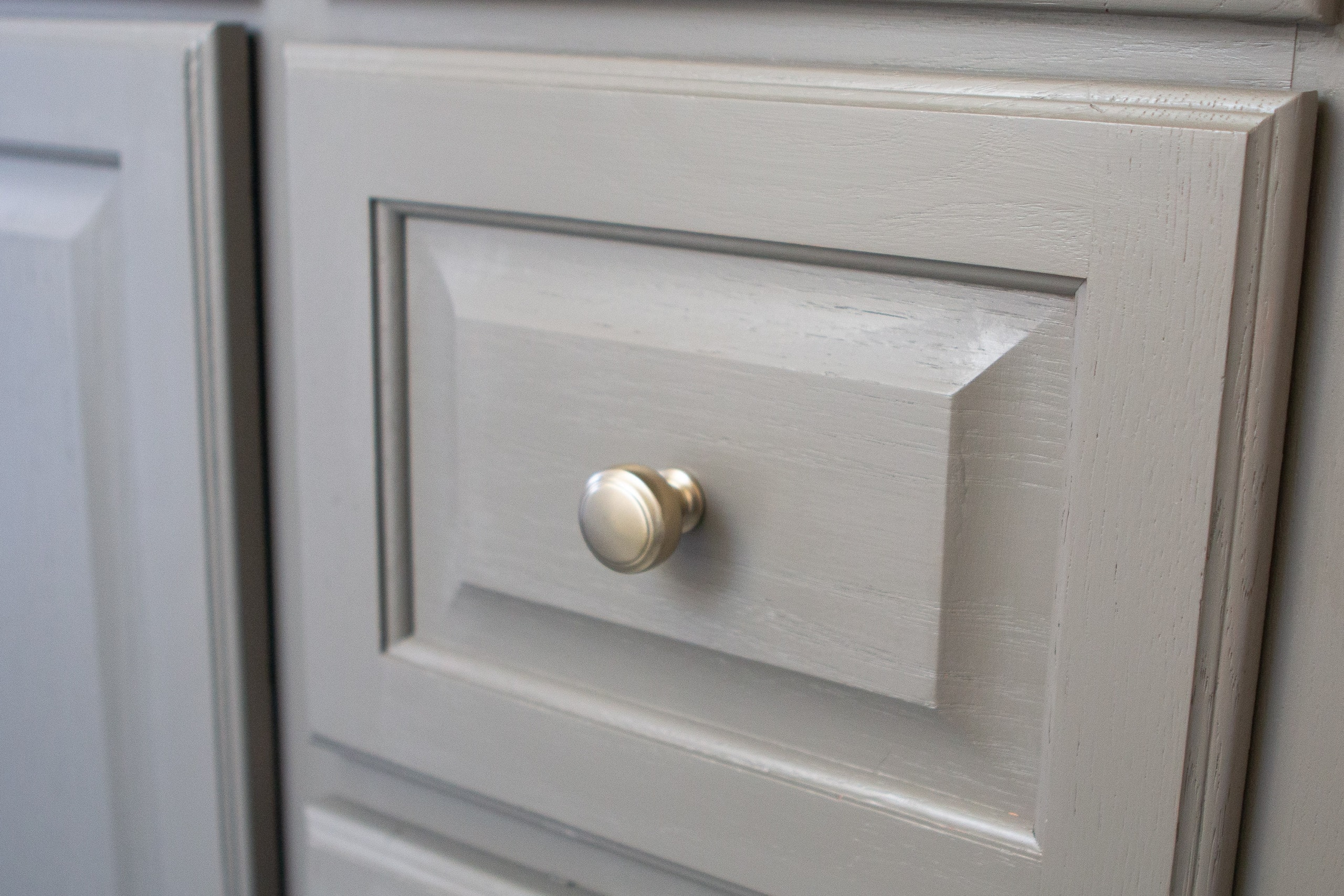 New gold knobs on a sage green cabinet