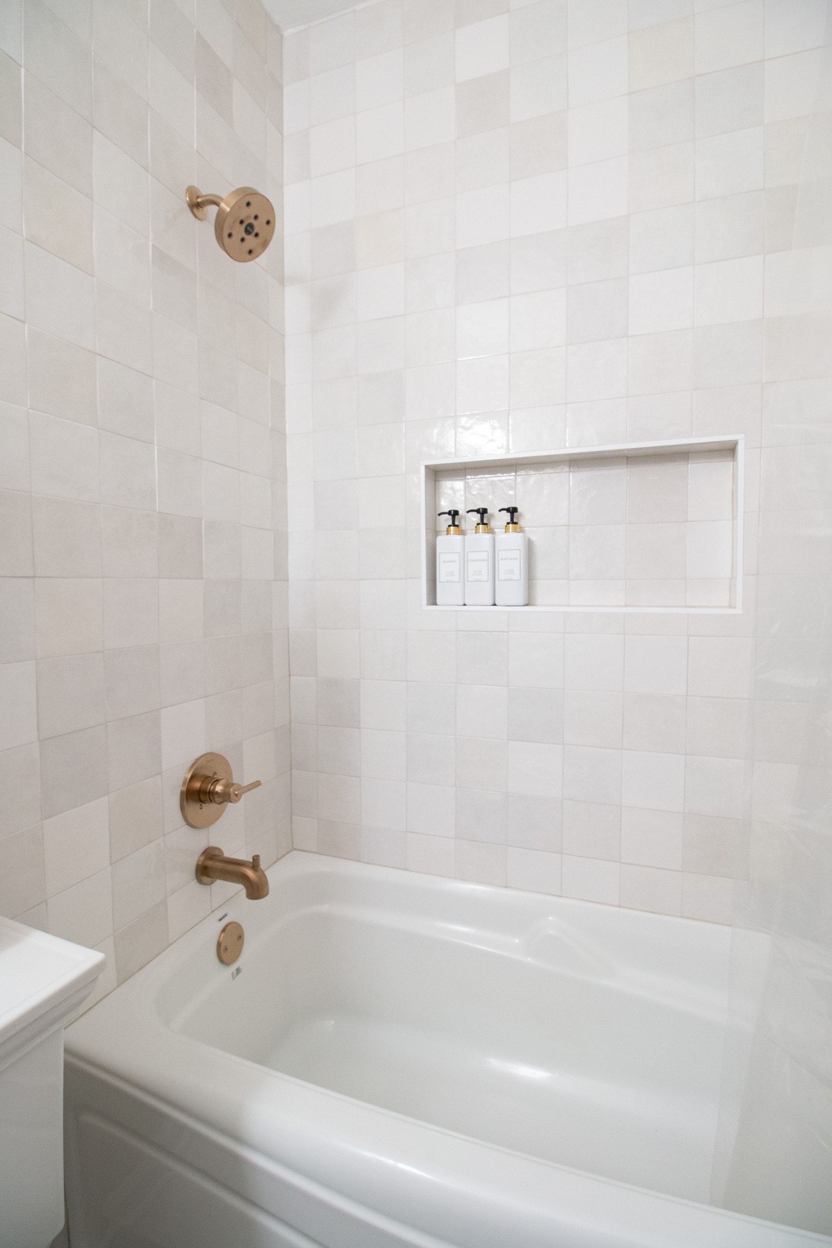 White shower tile in this gray and gold bathroom