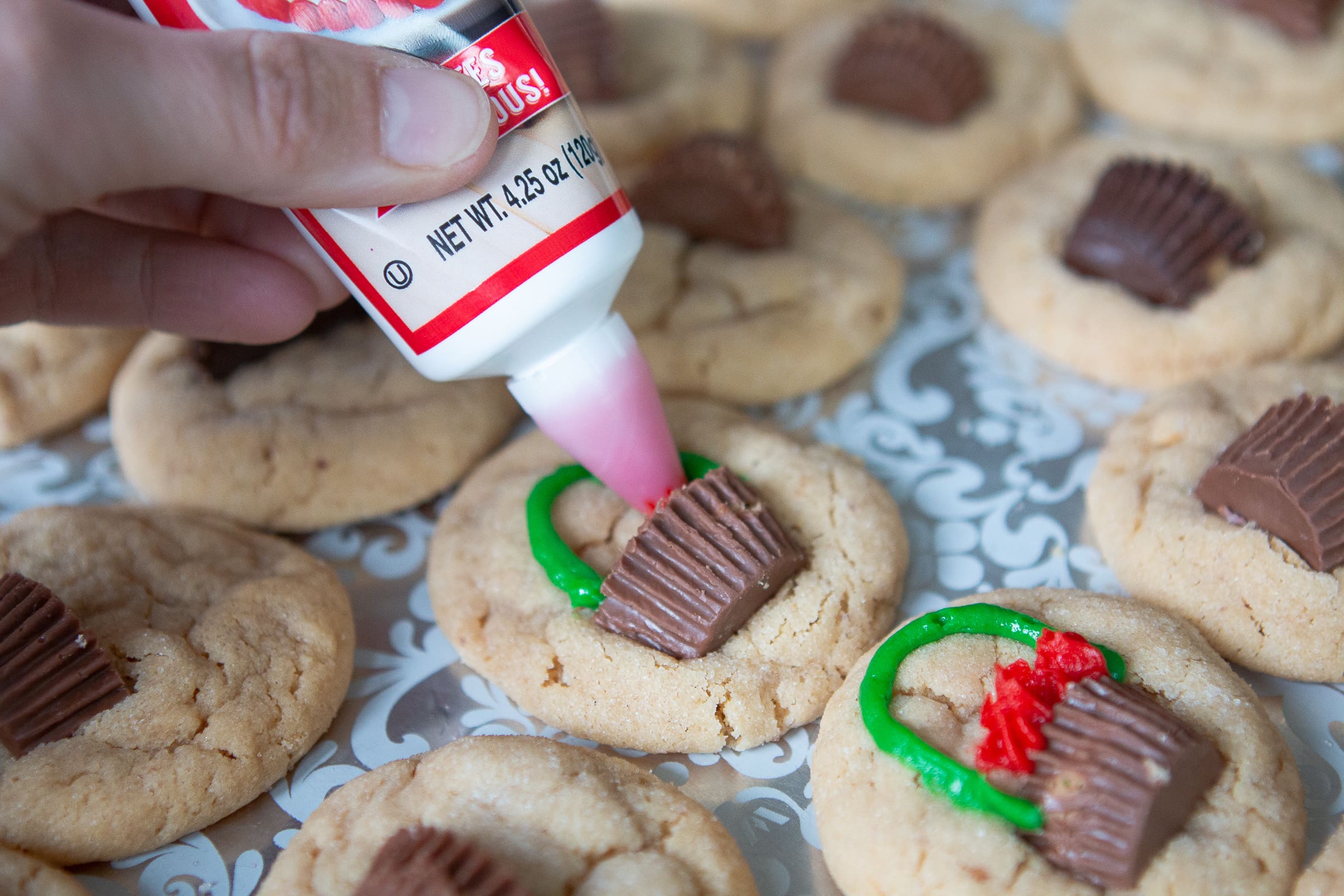 Adding red frosting to our peanut butter Christmas cookies